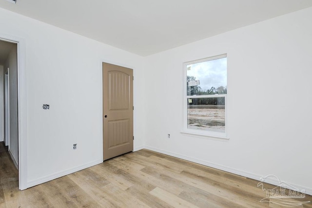 unfurnished room featuring light wood-style floors, visible vents, and baseboards