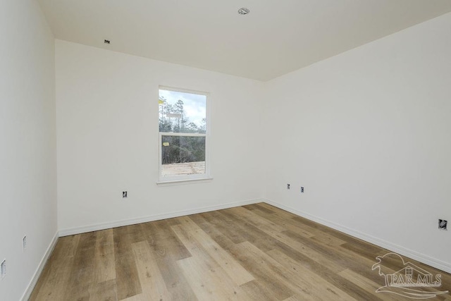 spare room with baseboards and wood finished floors