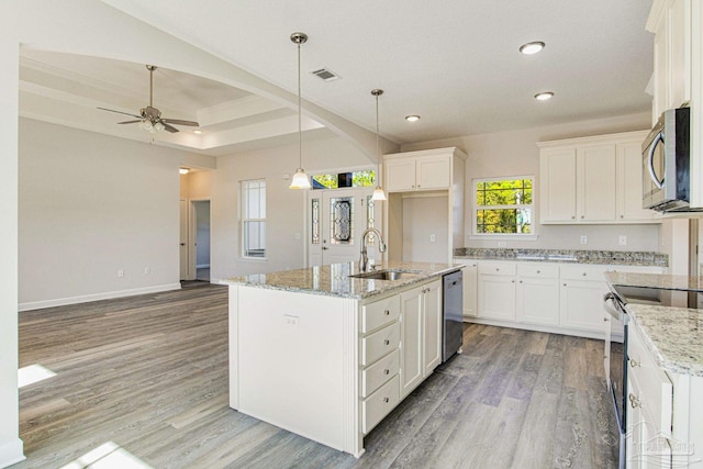 kitchen with a sink, white cabinets, appliances with stainless steel finishes, light wood-type flooring, and pendant lighting