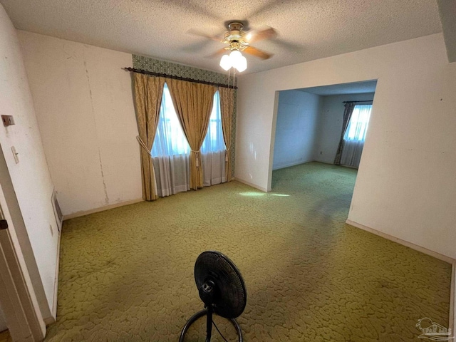 carpeted empty room with ceiling fan and a textured ceiling