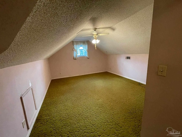 bonus room with vaulted ceiling, ceiling fan, a textured ceiling, and dark carpet