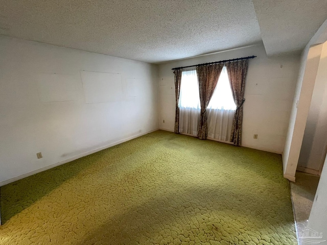 empty room with a textured ceiling and carpet flooring