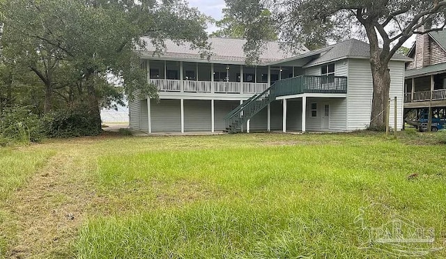 back of property featuring a deck, a sunroom, a yard, and stairway