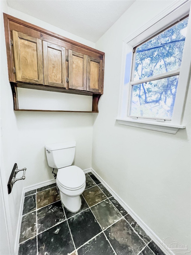 bathroom featuring toilet and baseboards