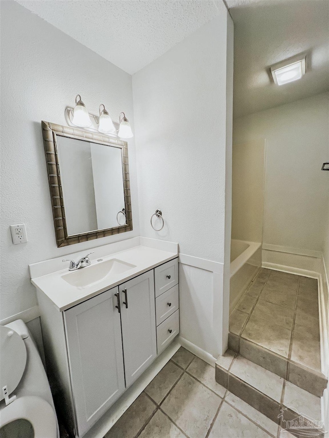 bathroom with a textured ceiling, toilet, vanity, and tile patterned floors