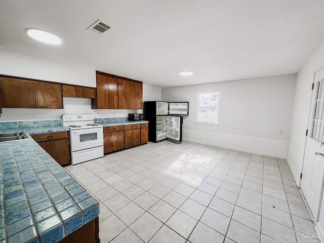 kitchen featuring white electric range oven, baseboards, visible vents, a textured ceiling, and a sink