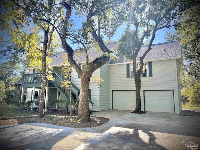 view of front facade featuring a shingled roof, driveway, a garage, and stairs