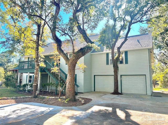 view of front of house with a garage, driveway, a shingled roof, and stairs