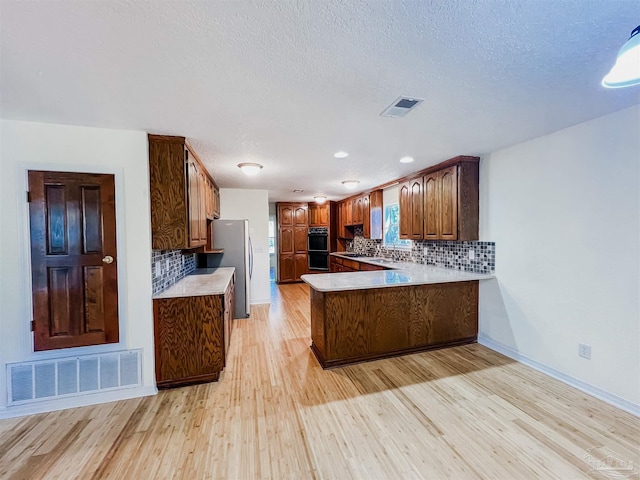 kitchen featuring light wood-type flooring, visible vents, and a peninsula