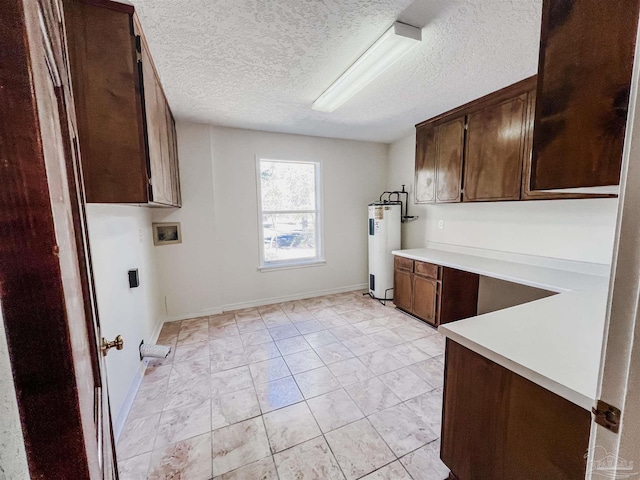 laundry area with electric water heater, a textured ceiling, hookup for a washing machine, and cabinet space