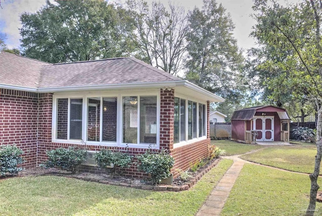 view of property exterior featuring a storage unit, a sunroom, and a lawn