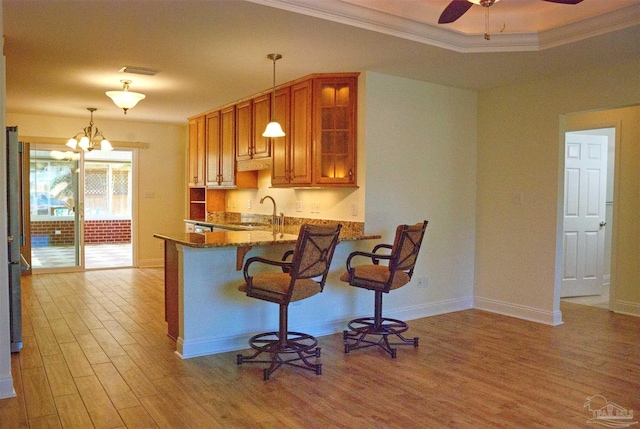 kitchen featuring crown molding, sink, a breakfast bar, and decorative light fixtures