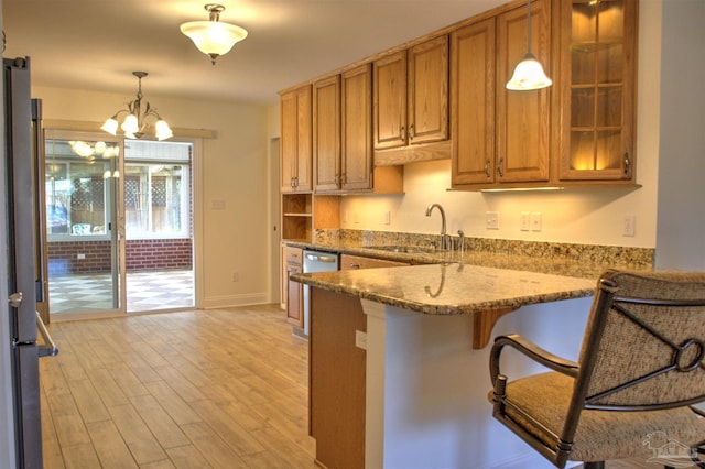 kitchen with sink, a breakfast bar area, stainless steel appliances, light stone countertops, and kitchen peninsula