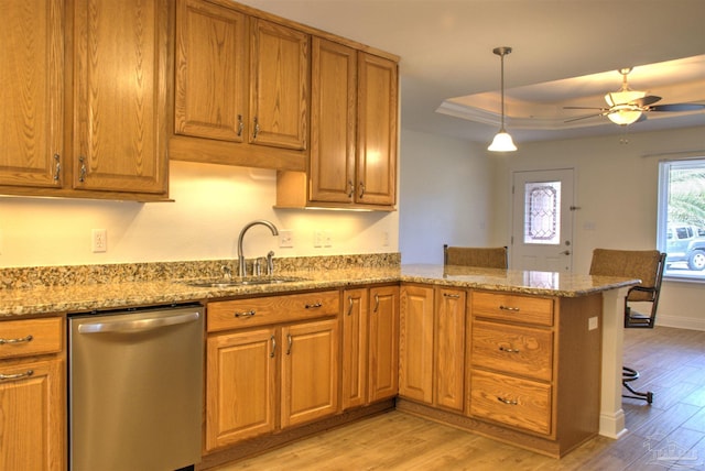 kitchen with sink, a tray ceiling, dishwasher, kitchen peninsula, and light stone countertops