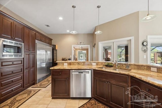 kitchen with built in appliances, sink, decorative light fixtures, and light tile patterned floors