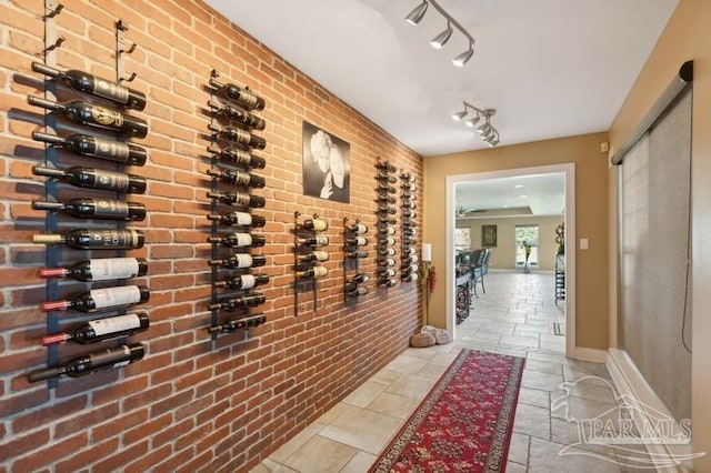 wine area with brick wall, rail lighting, and light tile patterned floors