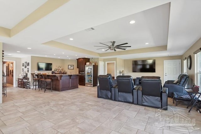 home theater featuring ceiling fan, a raised ceiling, and light tile patterned floors