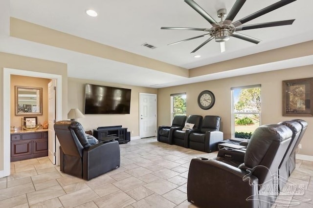 living room with a tray ceiling, ceiling fan, and light tile patterned floors