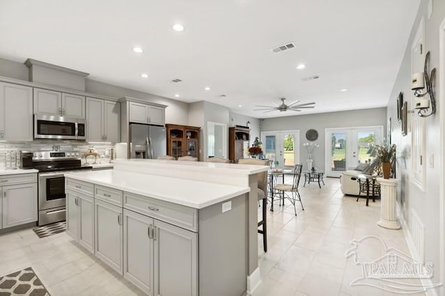 kitchen featuring appliances with stainless steel finishes, light tile patterned flooring, a center island, and ceiling fan