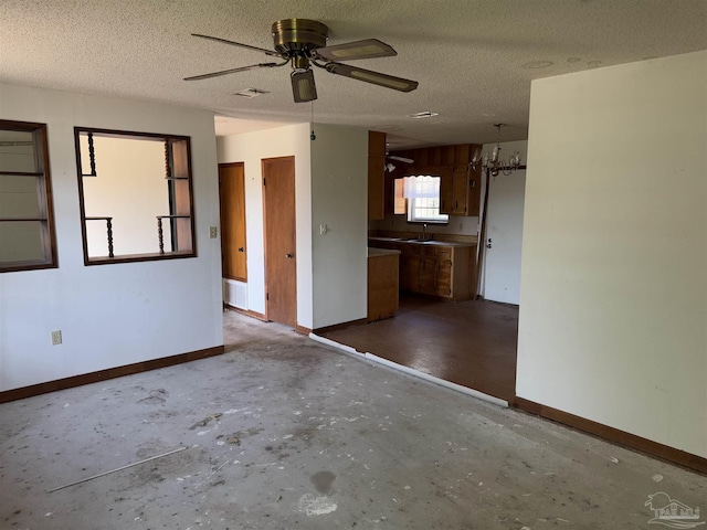 empty room featuring ceiling fan, sink, and a textured ceiling