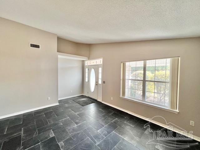 foyer entrance with vaulted ceiling and a textured ceiling