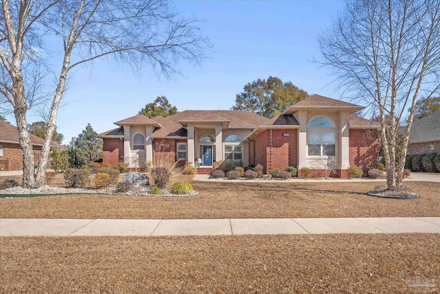 view of front of house featuring brick siding, stucco siding, and a front yard