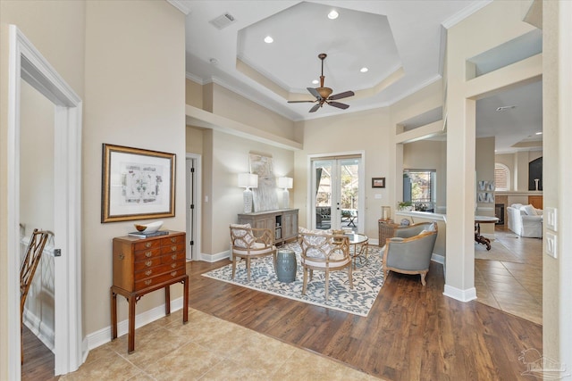 living area with a tray ceiling, french doors, crown molding, visible vents, and light wood-style floors