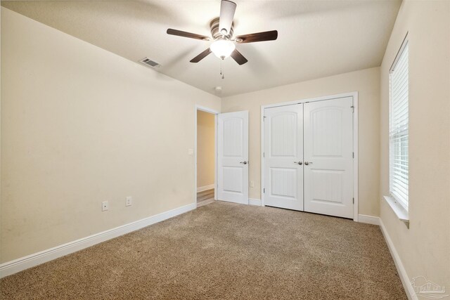 unfurnished bedroom featuring ceiling fan, visible vents, baseboards, a closet, and carpet