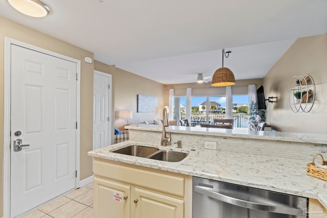 kitchen featuring stainless steel dishwasher, sink, light tile patterned flooring, hanging light fixtures, and cream cabinetry