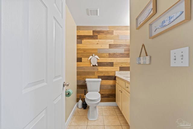 bathroom with toilet, tile patterned floors, wood walls, and vanity