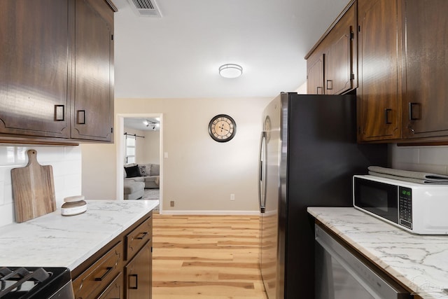 kitchen with visible vents, baseboards, dishwashing machine, light wood-style flooring, and backsplash