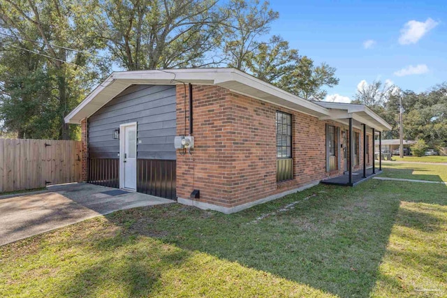 view of side of property featuring a yard, brick siding, and fence