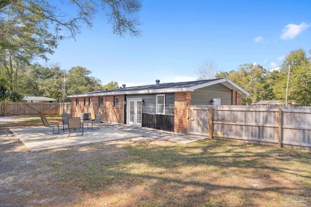 back of property with brick siding, a patio, a lawn, cooling unit, and a fenced backyard