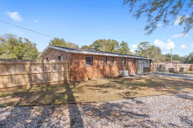 view of home's exterior with a fenced backyard, central air condition unit, brick siding, a yard, and a patio area