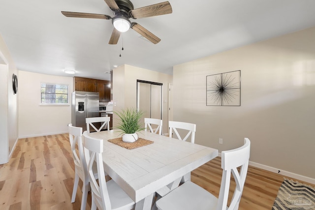 dining area with a ceiling fan, light wood-type flooring, and baseboards