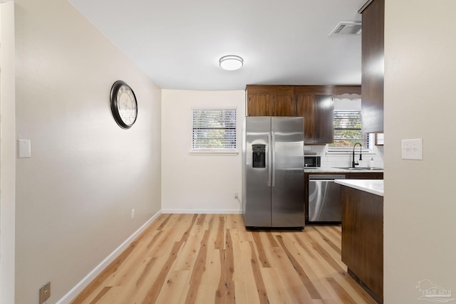 kitchen featuring light wood finished floors, visible vents, appliances with stainless steel finishes, light countertops, and a sink