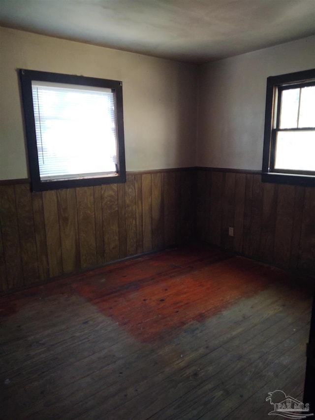 spare room with a wainscoted wall, dark wood-style floors, and wooden walls