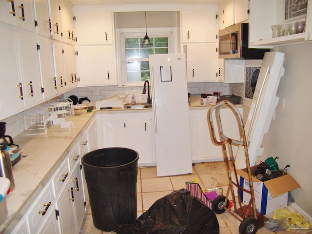 kitchen featuring sink, white cabinets, and decorative light fixtures