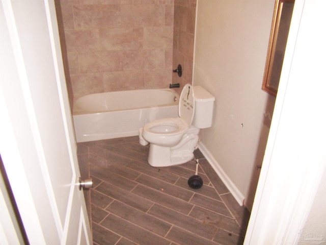 bathroom with toilet and tiled shower / bath combo