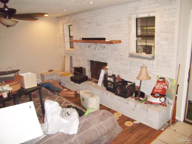 living room with ceiling fan, wood-type flooring, and a brick fireplace