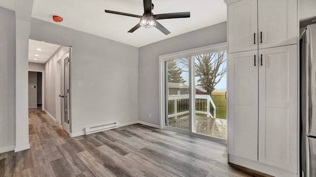 empty room featuring ceiling fan, a baseboard radiator, and light wood-type flooring