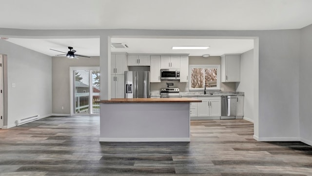 kitchen with white cabinets, wood-type flooring, baseboard heating, and appliances with stainless steel finishes