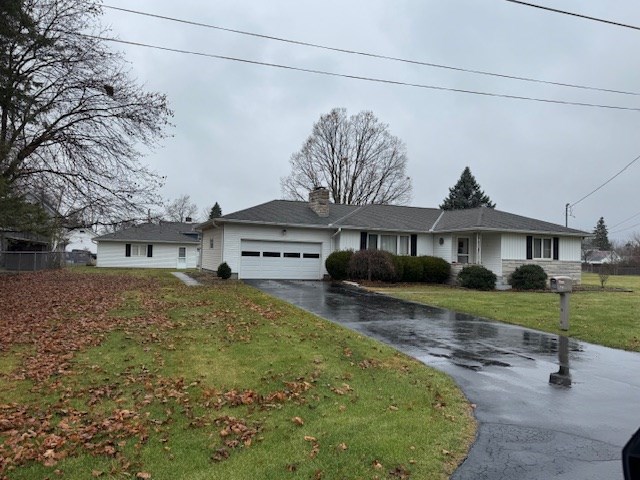 single story home with a garage and a front lawn