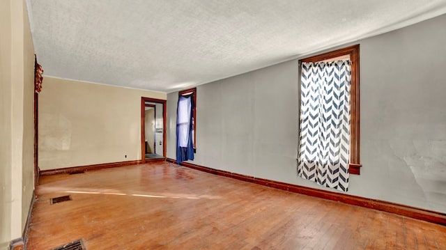 empty room with wood-type flooring and a textured ceiling