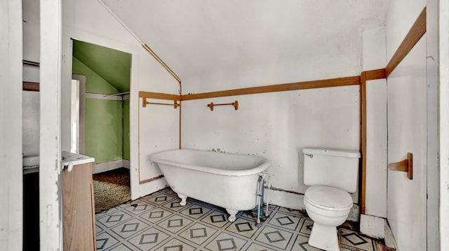 bathroom featuring a washtub, toilet, and vaulted ceiling