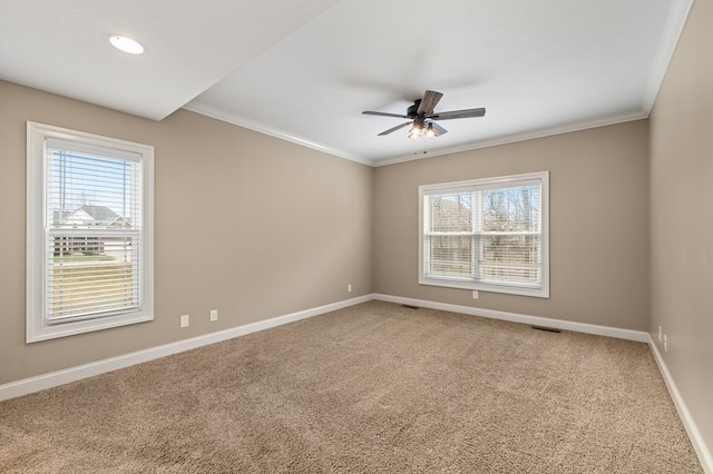 carpeted spare room with ceiling fan, ornamental molding, and a wealth of natural light