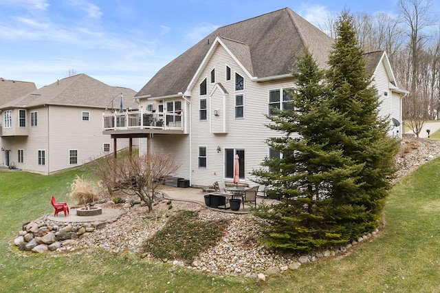 rear view of house with a fire pit, a lawn, a patio, and a balcony