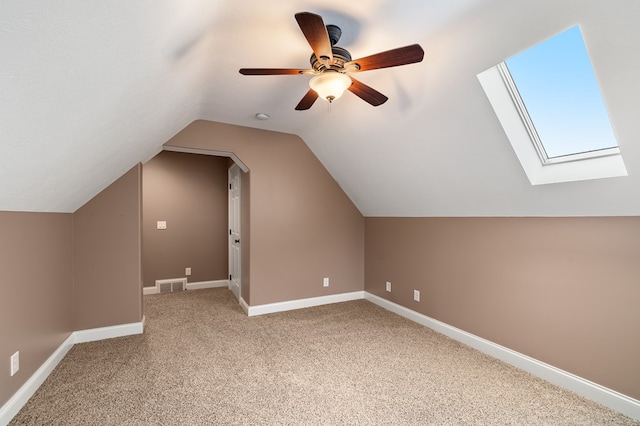 additional living space with lofted ceiling with skylight, carpet floors, and ceiling fan