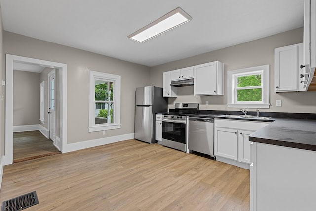 636 Callowhill St, Wooster, OH 44691 - kitchen with appliances with stainless steel finishes, a sink, dark countertops, under cabinet range hood, and light wood-style flooring