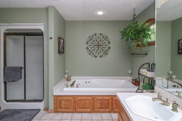 bathroom featuring a textured ceiling, tile patterned flooring, a garden tub, vanity, and a stall shower